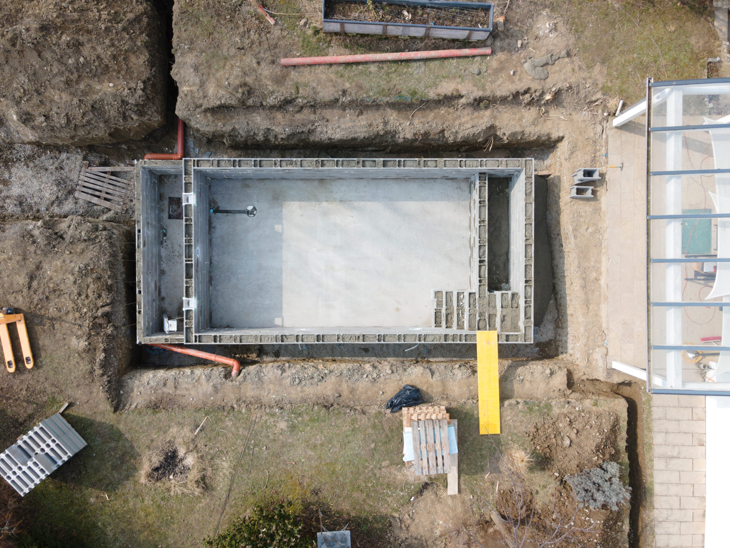 aerial drone shot of pool construction site, form blocks being filled with concrete
